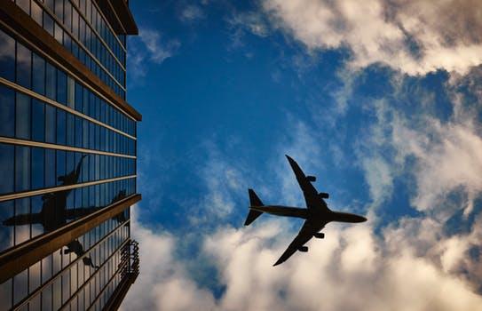 Plane Flying Over a Glass Building - 8 Business Travel Hacks to Make it More Comfortable